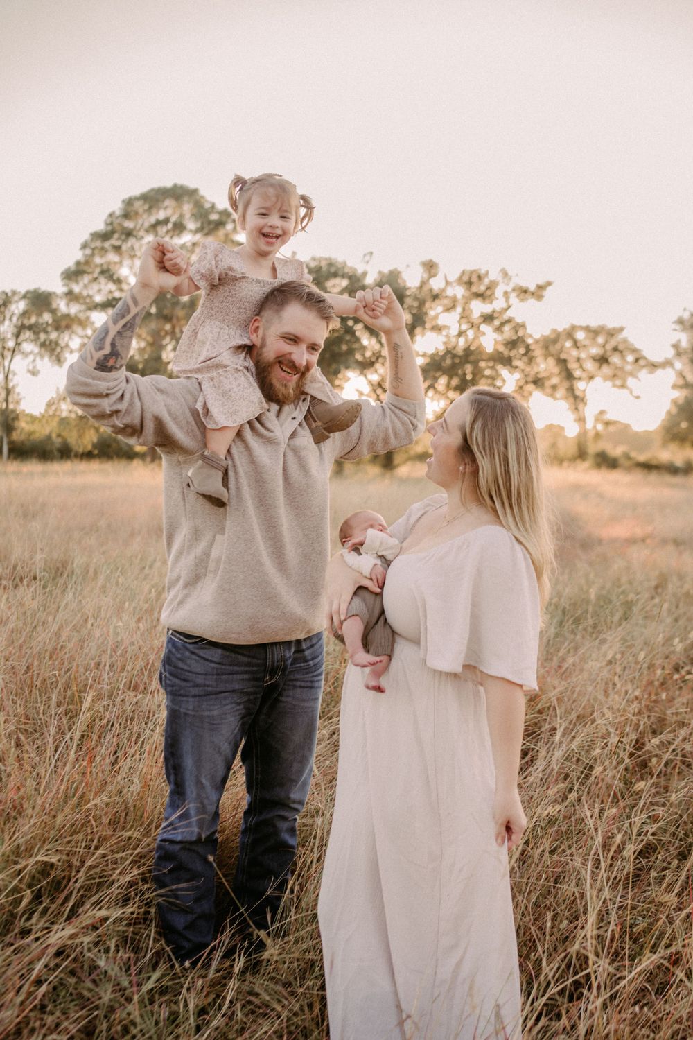 A family enjoying a warm sunset moment together in a golden field with tall grass.