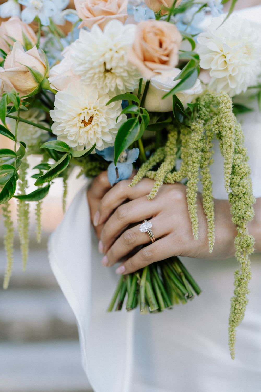 Elegant bridal bouquet with white and peach roses, showing wedding ring detail.