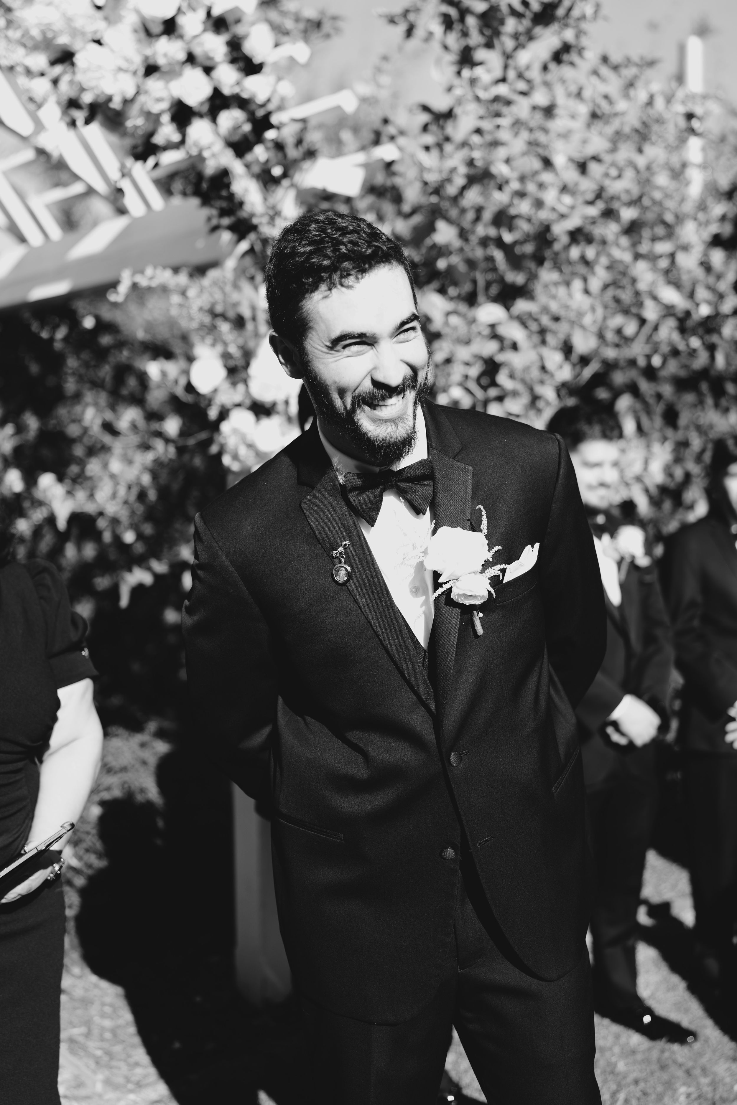 Black and white photo showing emotional reactions during a wedding ceremony outdoors.