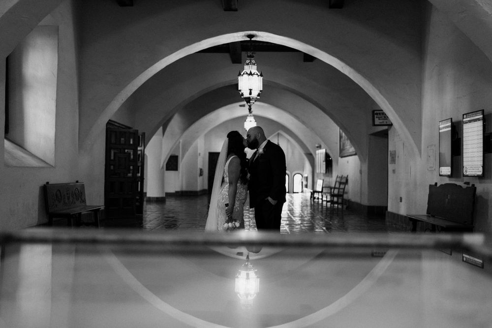 Black and white photo of a grand arched hallway with reflected light on the polished floor.