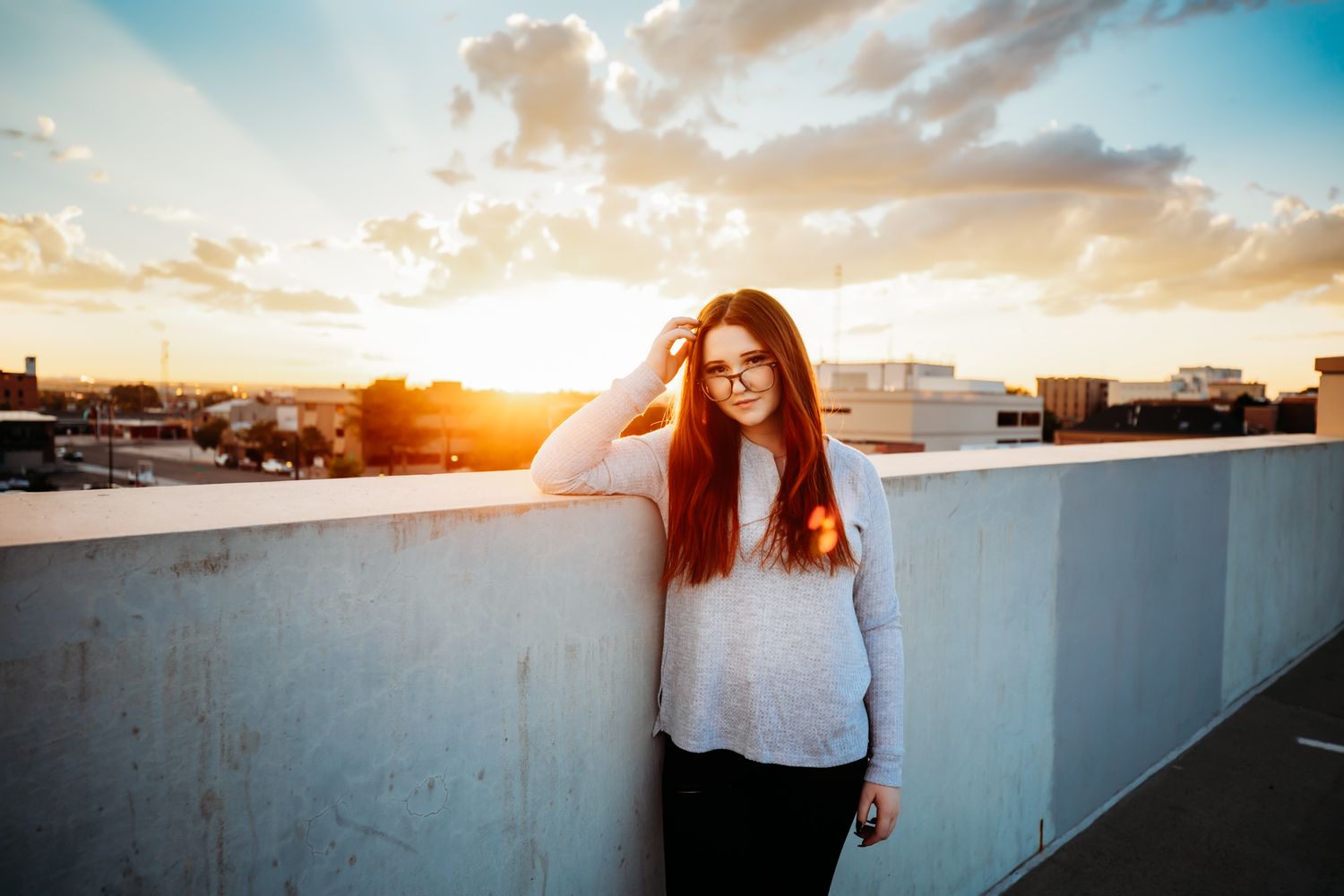 Senior girl with red hair smiling on rooftop at sunset in Dickson, TN