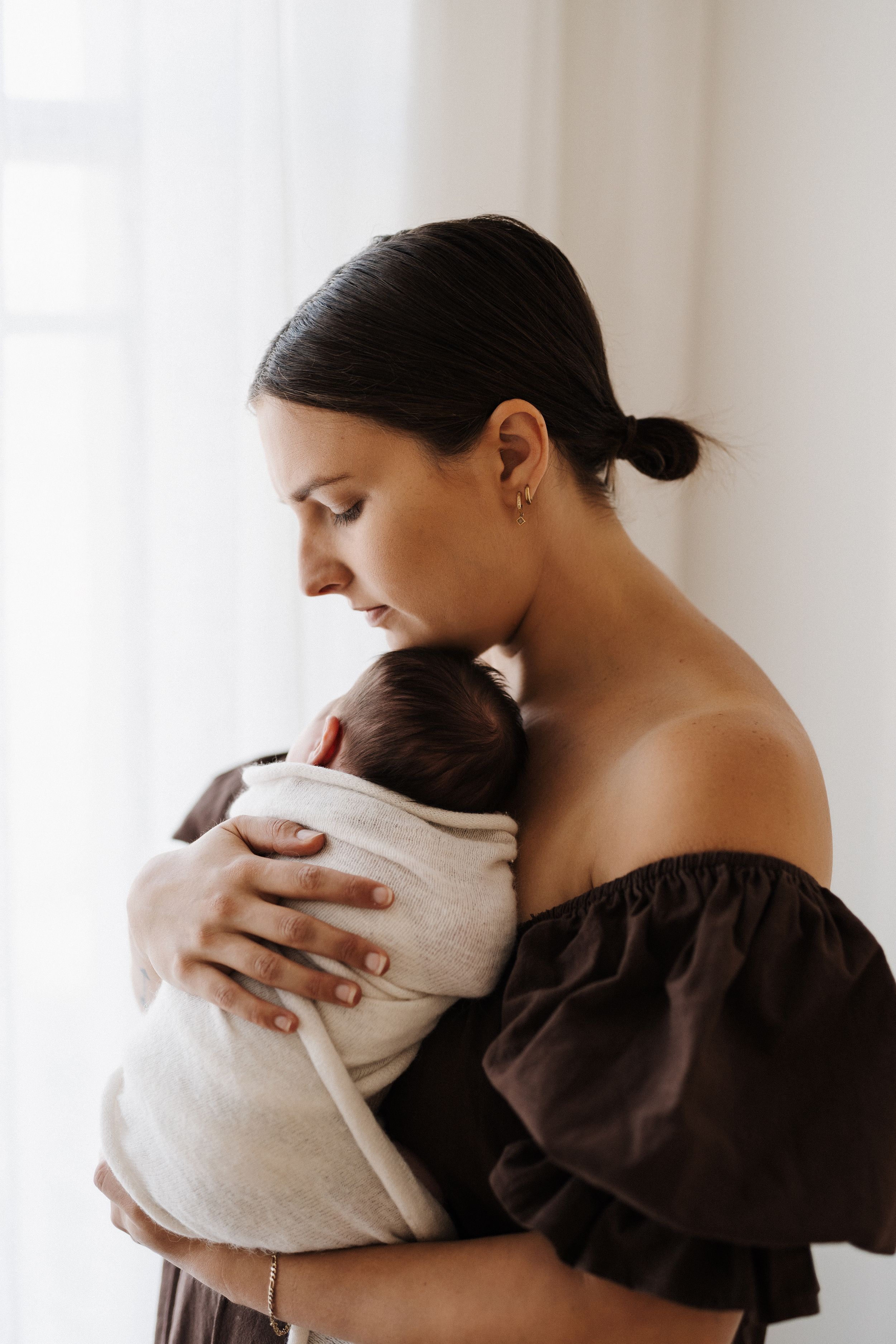 Intimate black and white portrait of maternal bonding in minimalist studio setting.