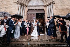 Wedding party gathering outside a historic stone church entrance.