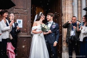 Newlyweds celebrating with guests throwing confetti outside a historic church entrance.