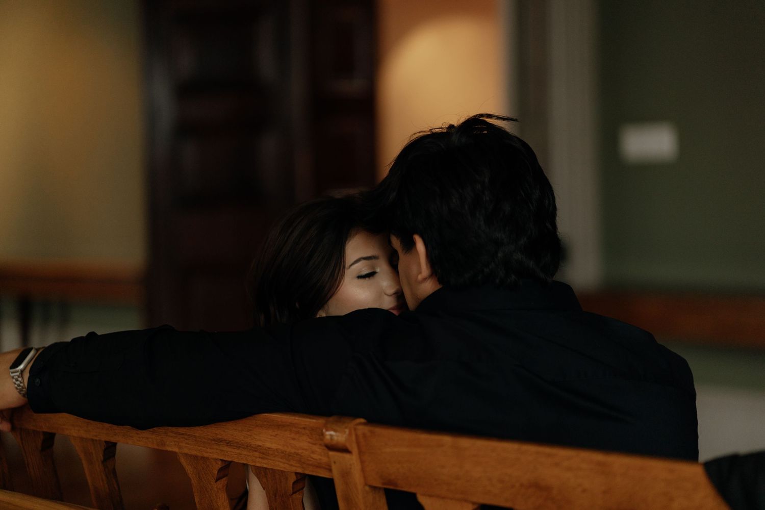 A silhouetted couple shares a romantic moment in a dimly lit indoor setting.