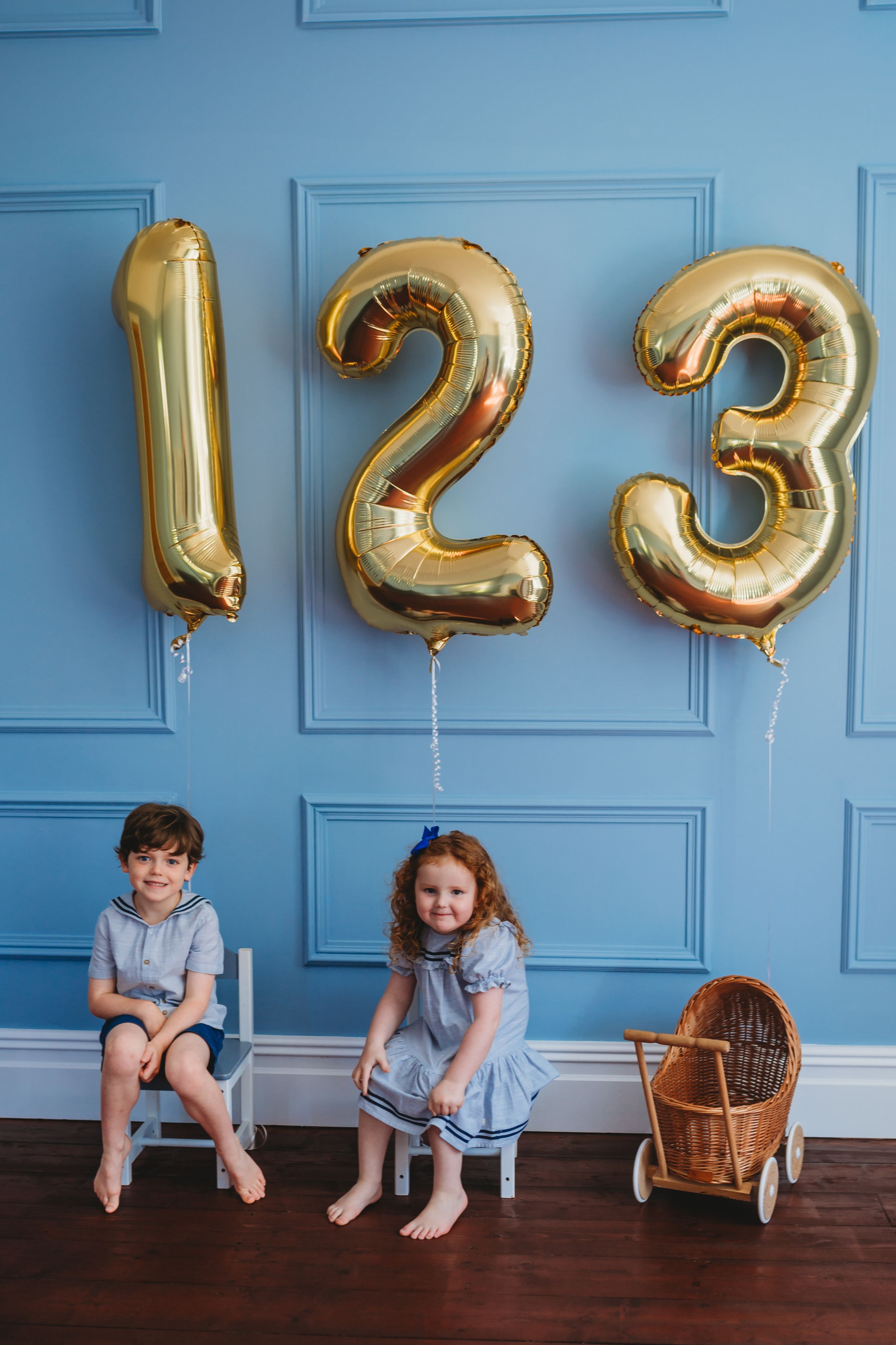A series of photos showing two children sitting against a blue wall with large gold number balloons showing a countdown.