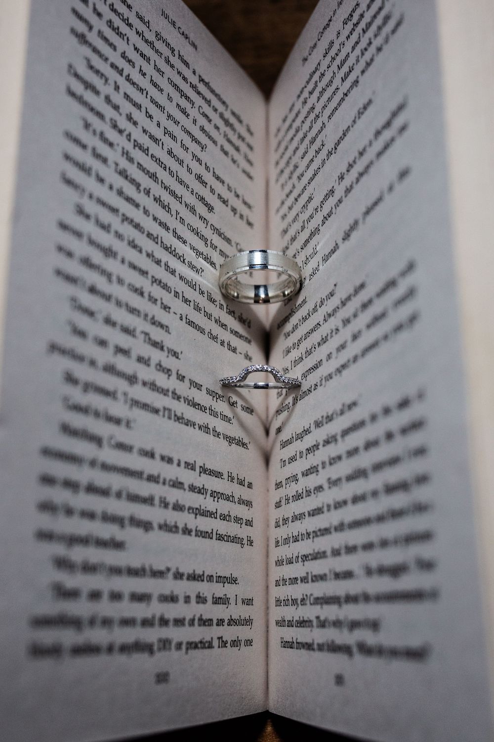 Wedding rings nestled between pages of an open book create romantic shadows and reflections.