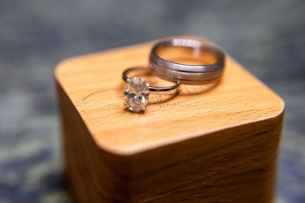 Diamond engagement ring and wedding band resting on a wooden ring box, elegant jewelry photography.