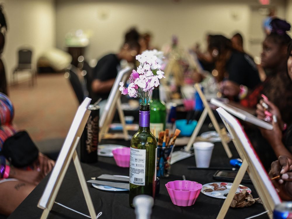 A dining table setup with wine bottles and pink flower decorations at a social gathering event.