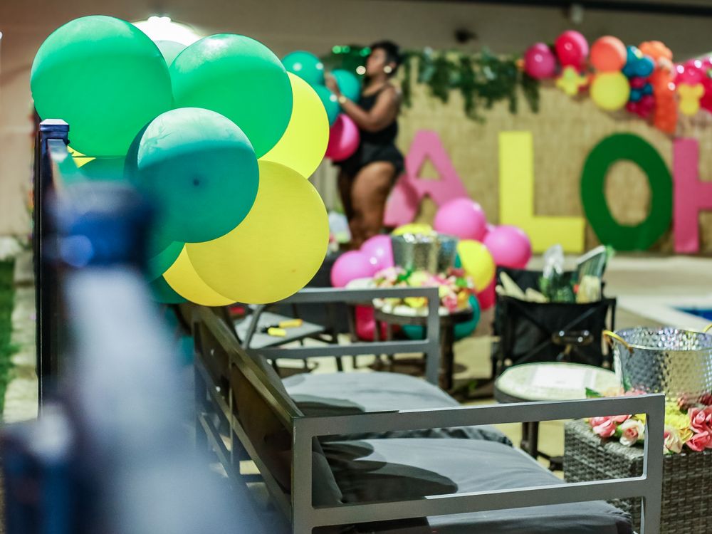 Colorful balloons decorate an office space with green, blue, and pink balloons hanging above desks and workstations.