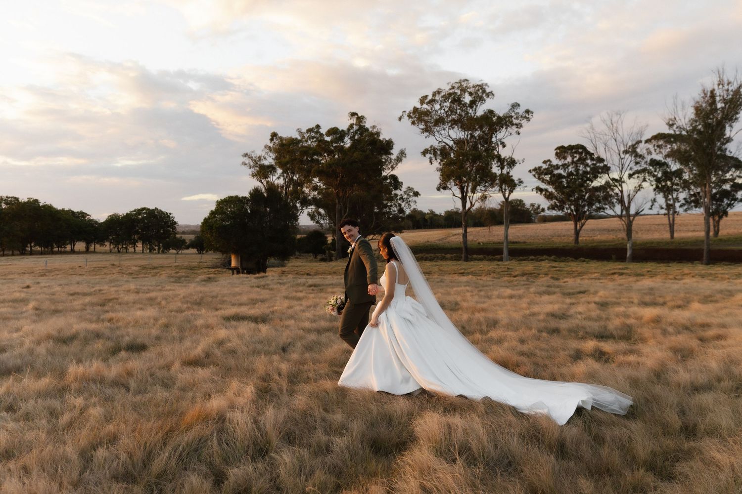 Romantic sunset moment between newlyweds in a green meadow.