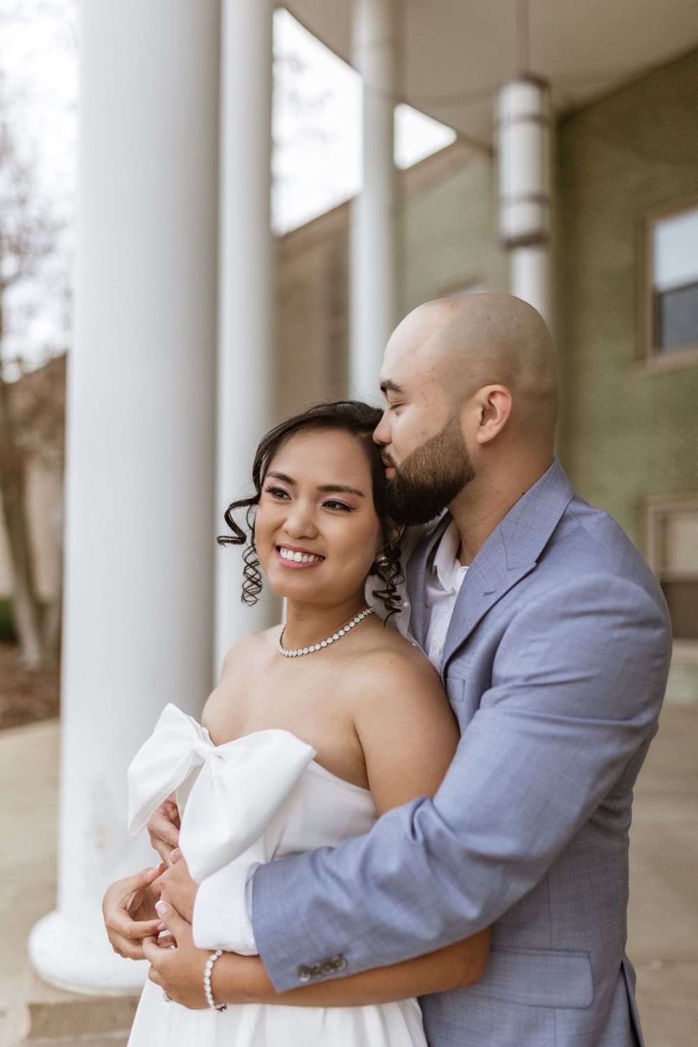 Tender embrace captured against classic architectural backdrop with white columns.