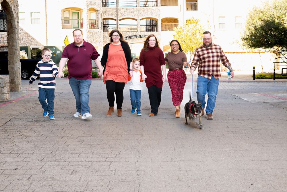 Extended family walking together outdoors in coordinated burgundy and plaid outfits.