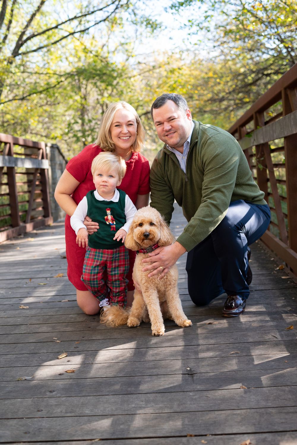 Family portrait on wooden bridge with goldendoodle puppy in autumn setting.