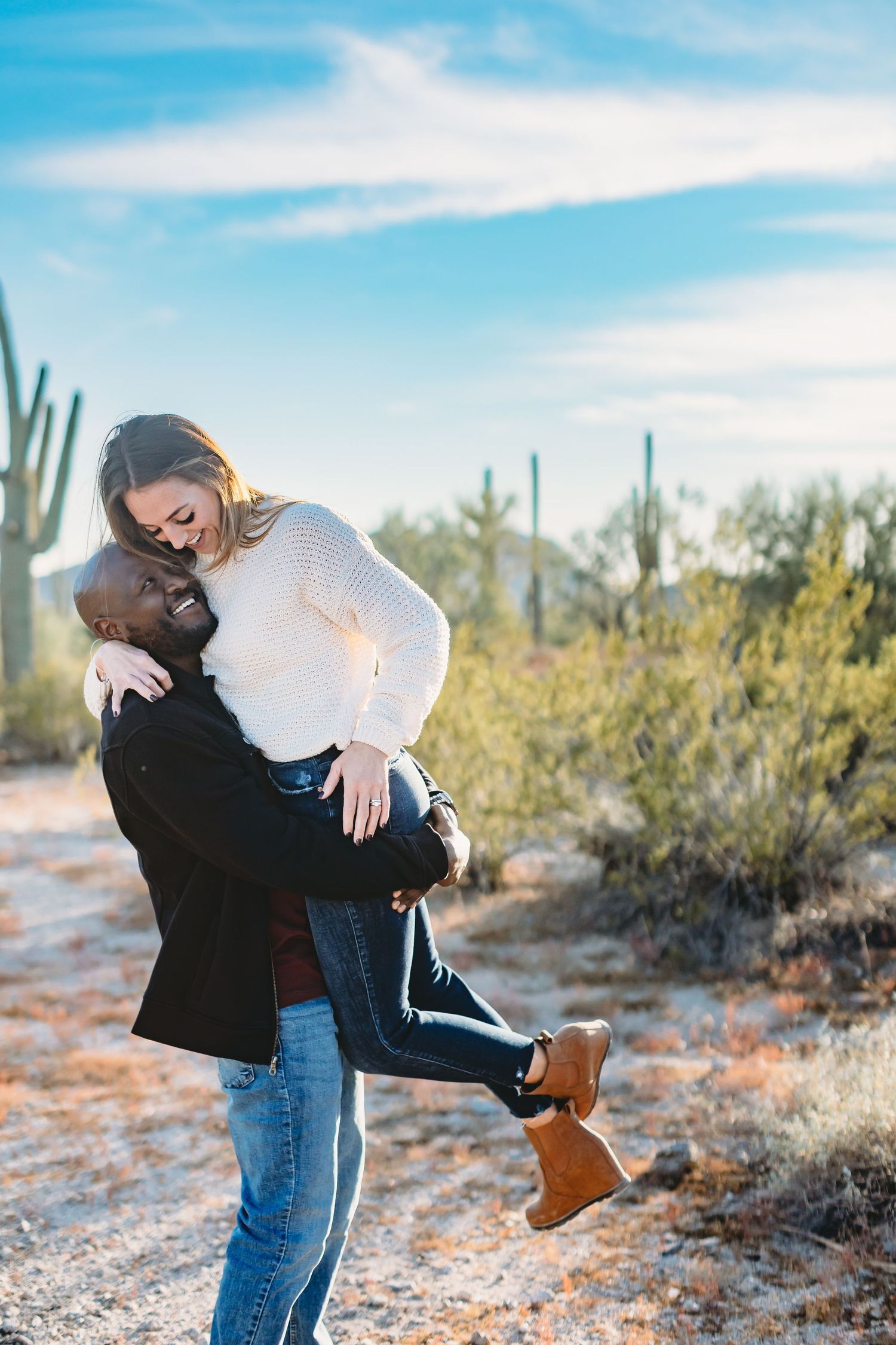 Romantic couple sharing a playful moment in a desert setting with saguaro cacti.