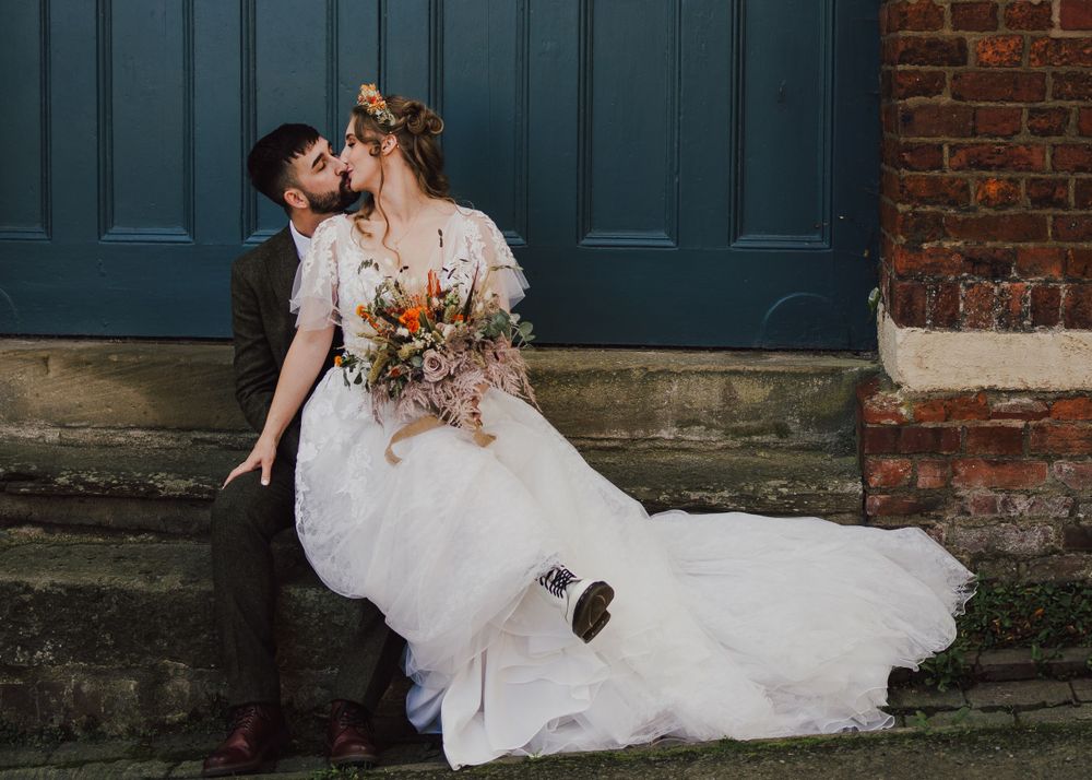 Romantic portrait of newlyweds against a blue door with bride's lace dress flowing.