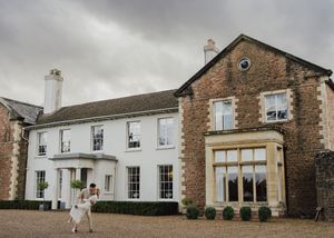 A panoramic view of a rustic brick and stone wedding venue with white trim and classic architectural details.