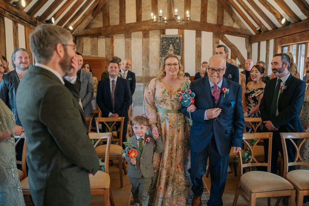A wedding ceremony in a rustic wooden barn with exposed beams and candles as guests look on from wooden chairs.