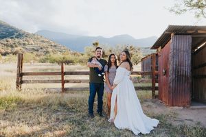 Outdoor family portrait session against backdrop of desert mountains and rustic buildings.