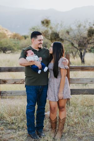 Casual family photos taken in desert setting with wooden fencing and mountain views.