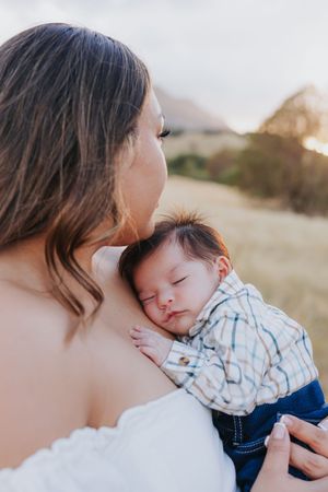 Tender moment between parent and baby during sunset desert photoshoot.