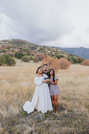 Joyful family photos taken in golden desert grassland with mountains in background.