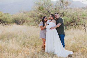 Intimate family moment captured in desert landscape with mountains in background.