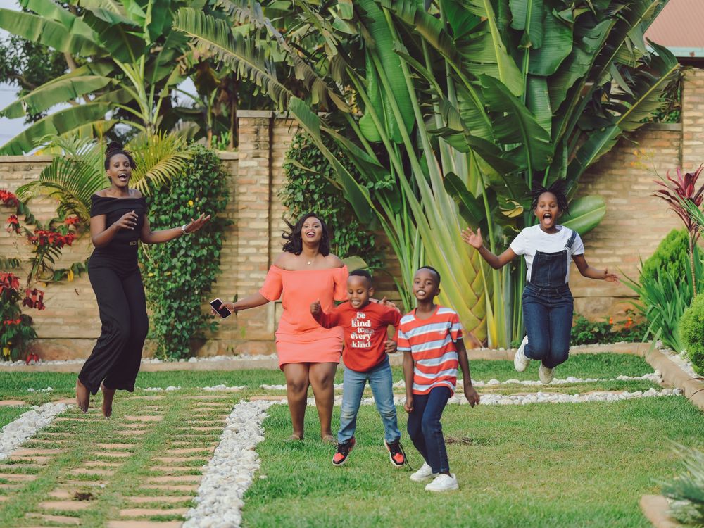 Family enjoying playful moments together in a lush garden with banana plants.