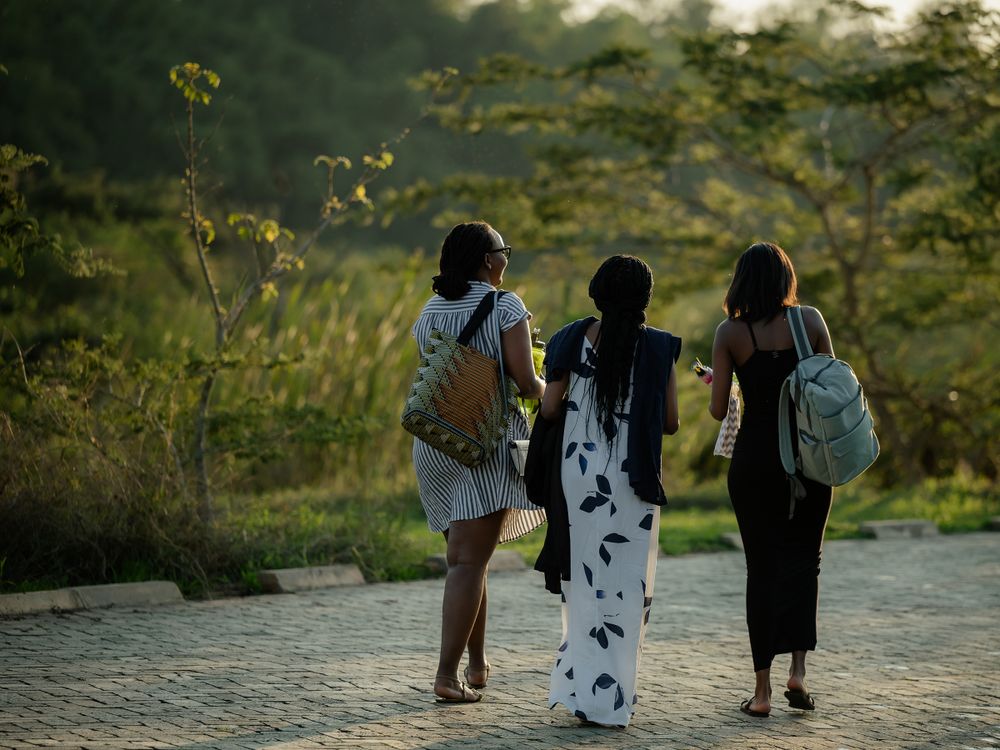 Three friends walking together on a path during golden hour with backpacks.