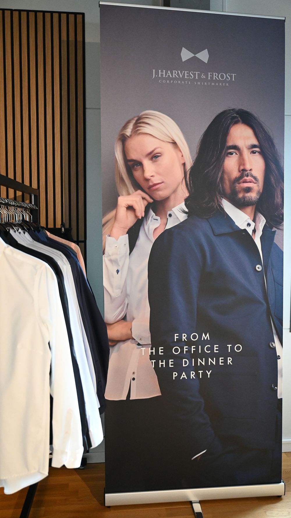 Fashion advertisement display showing elegant office and formal wear with promotional posters and hanging white garments.