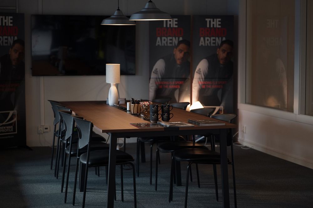 A dimly lit restaurant interior with dark wood tables and chairs arranged in rows during evening hours.