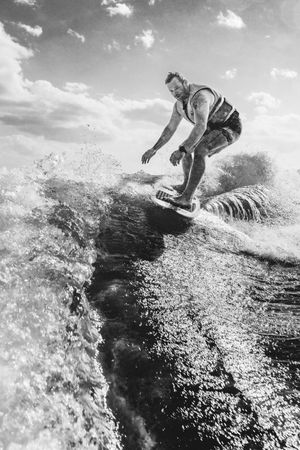 Black and white sequence of a surfer riding a powerful wave with dramatic spray and motion captured over four frames.