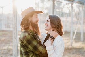Romantic outdoor engagement photos in warm sunlight with couple wearing plaid and white against natural backdrop.