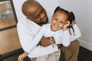 A playful parent and child photoshoot with matching white outfits and joyful expressions.