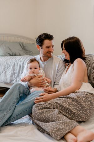 A couple relaxes on a bed with their baby in a series of candid lifestyle photos showing tender family moments.