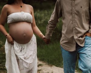 A series of maternity photos showing a couple's hands lovingly cradling a pregnant belly in an outdoor garden setting.