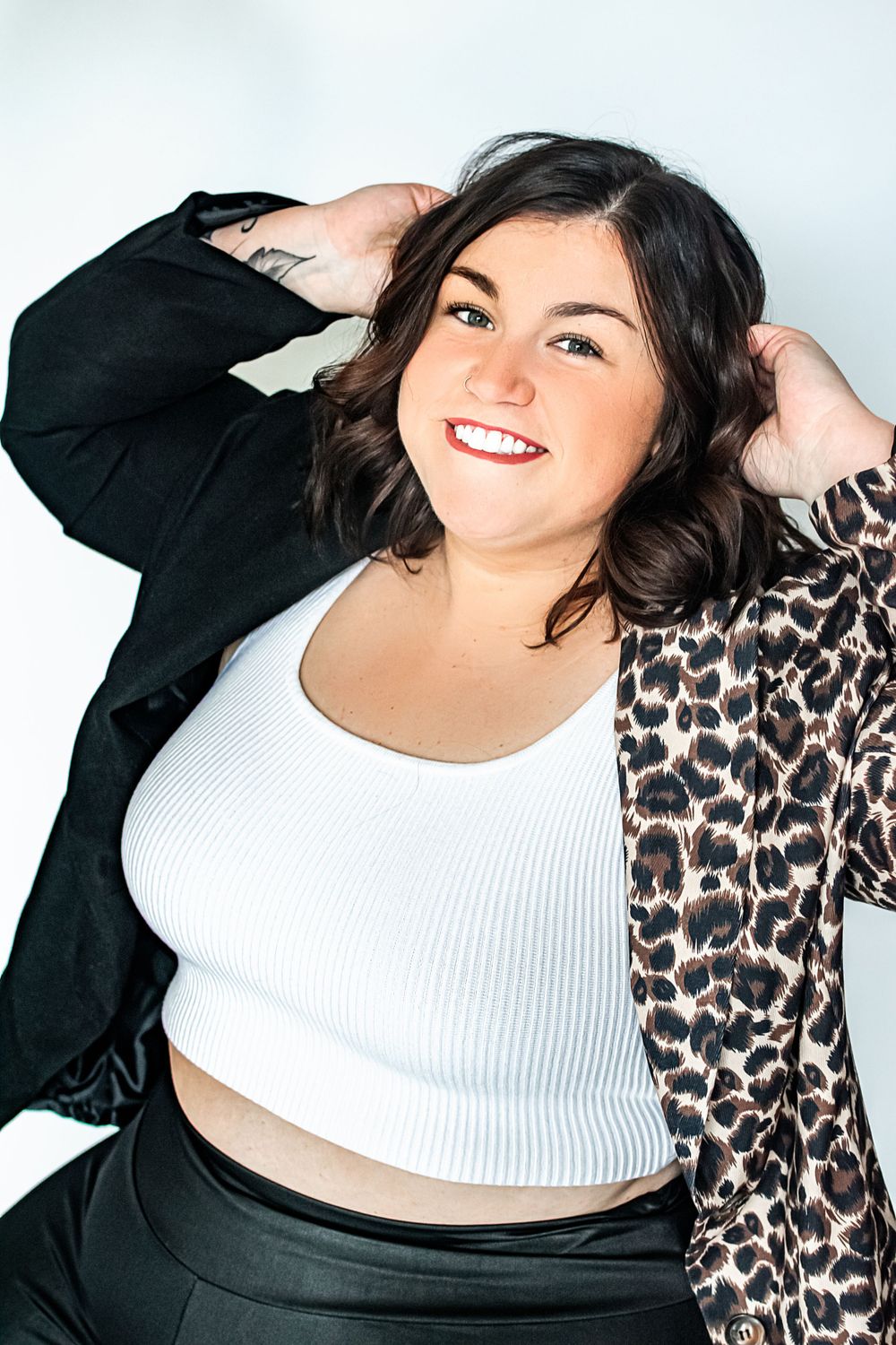 Woman in white crop top and leopard print jacket posing confidently.