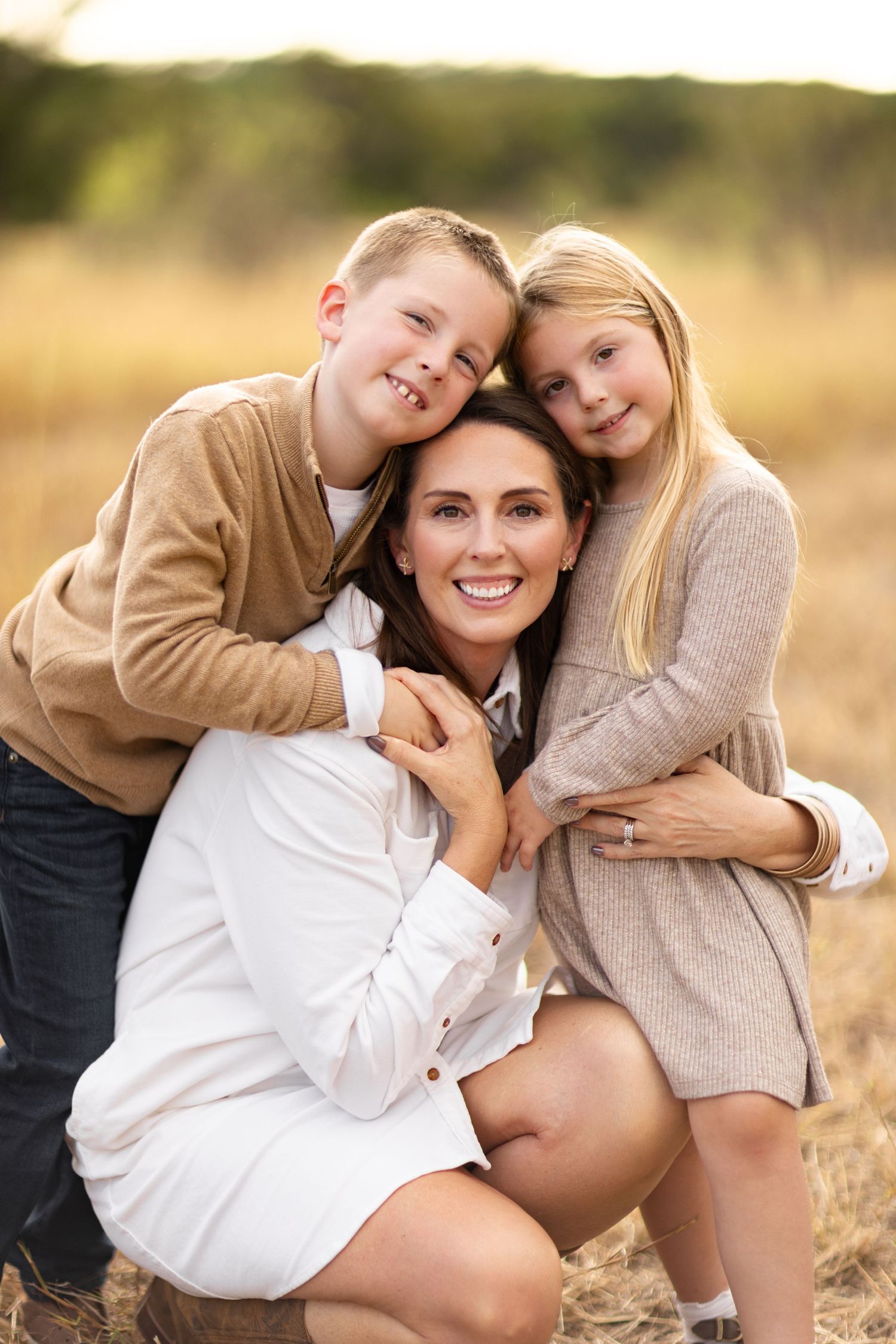 Maternity photo series in warm tones showing tender family moments in a field.