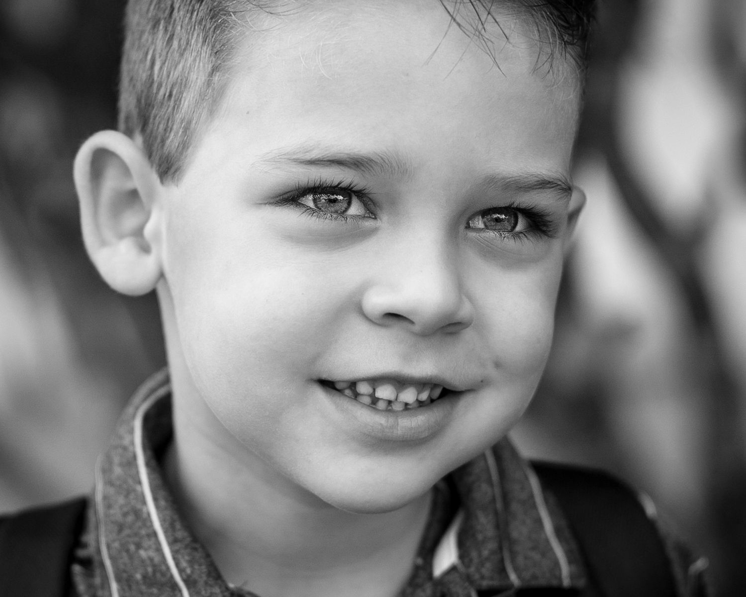 Close-up black and white portrait of a young child with a bright genuine smile.