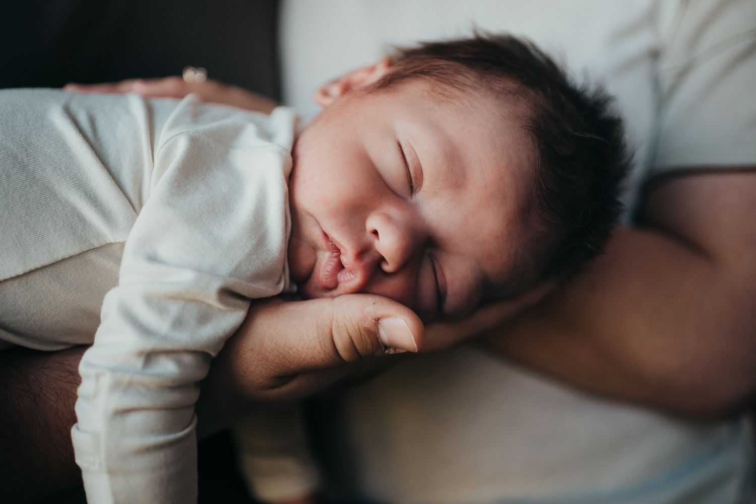 Lifestyle newborn photography in Dickinson, ND - cozy in-home session with neutral tones, capturing newborn snuggles