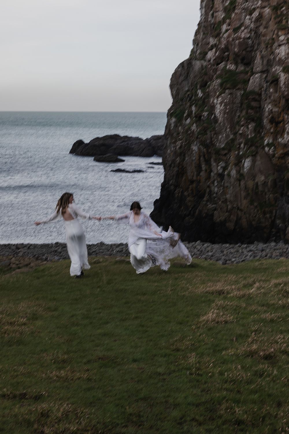 LGBTQ couple holding hands and dancing by the Dunseverick castle in Northern Ireland during their elopement