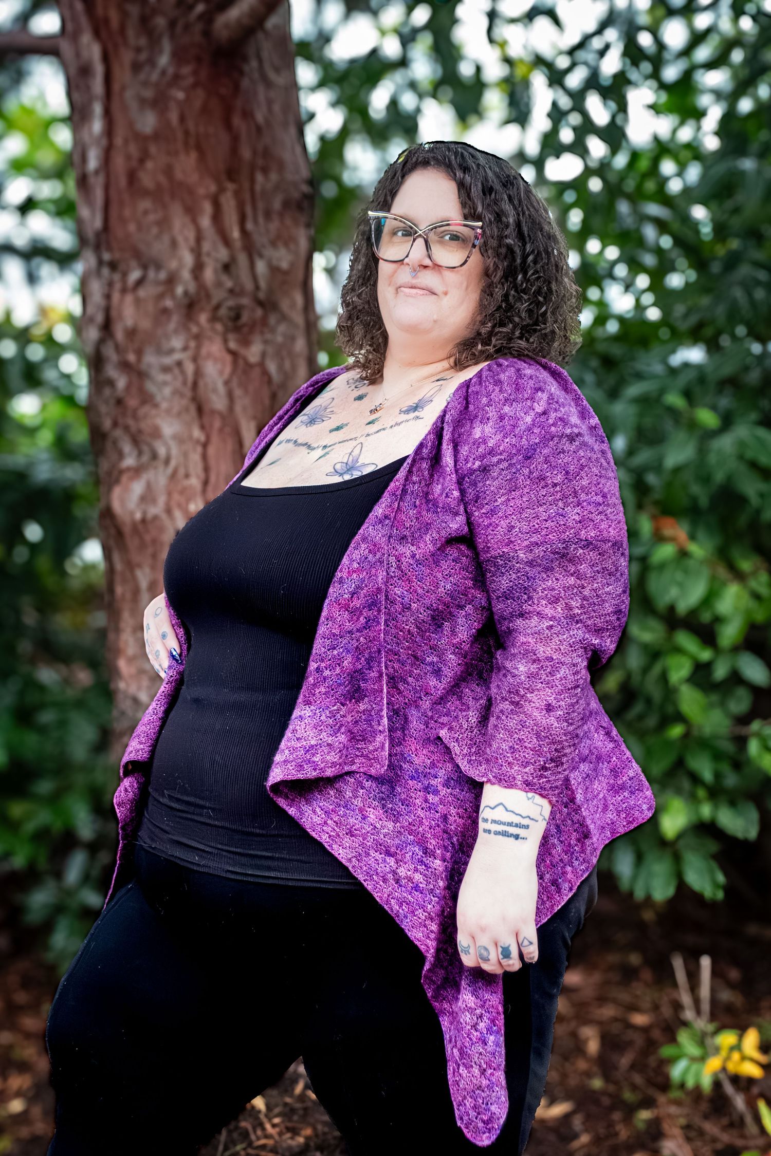 Photographer holding professional camera equipment with tattoo visible on arm.