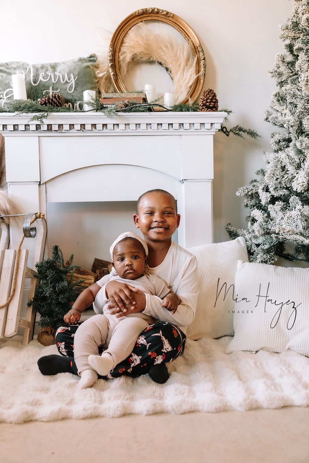 Christmas photo session with babies laying on white fur in front of decorated mantel and tree.