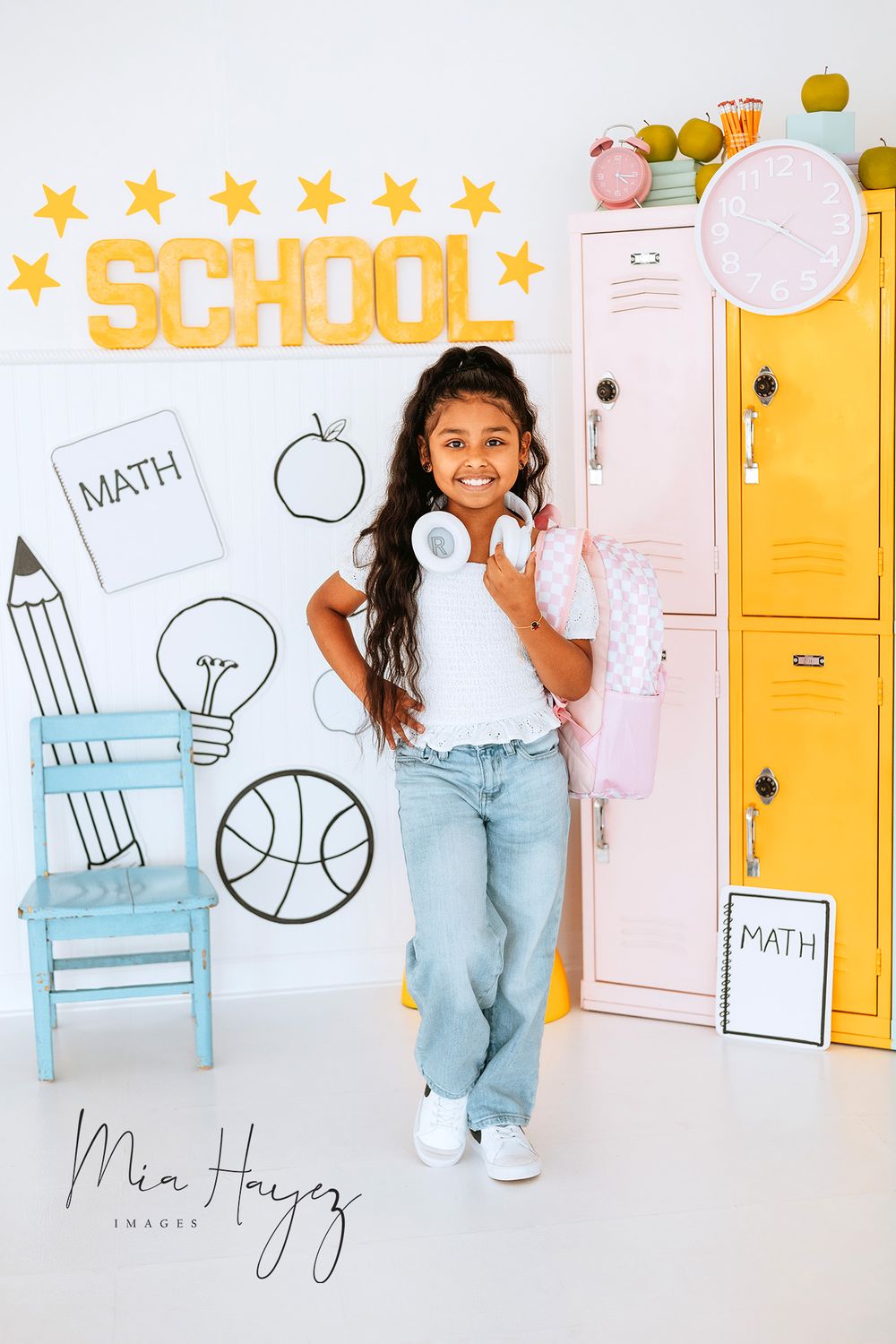 School-themed photoshoot with lockers, chairs, and educational decorations.