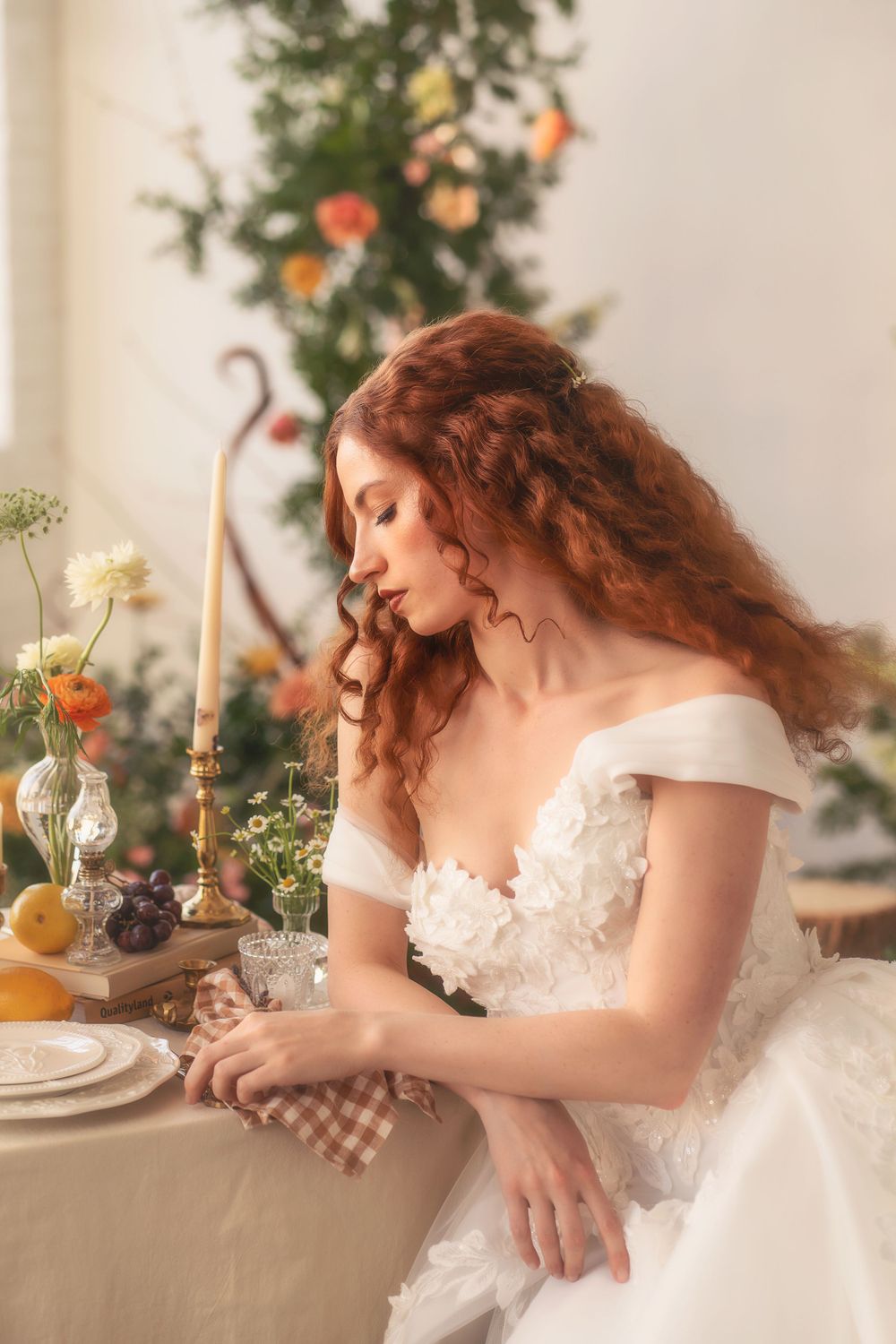 A romantic scene features a woman in a white dress seated at a decorated table with flowers and place settings.