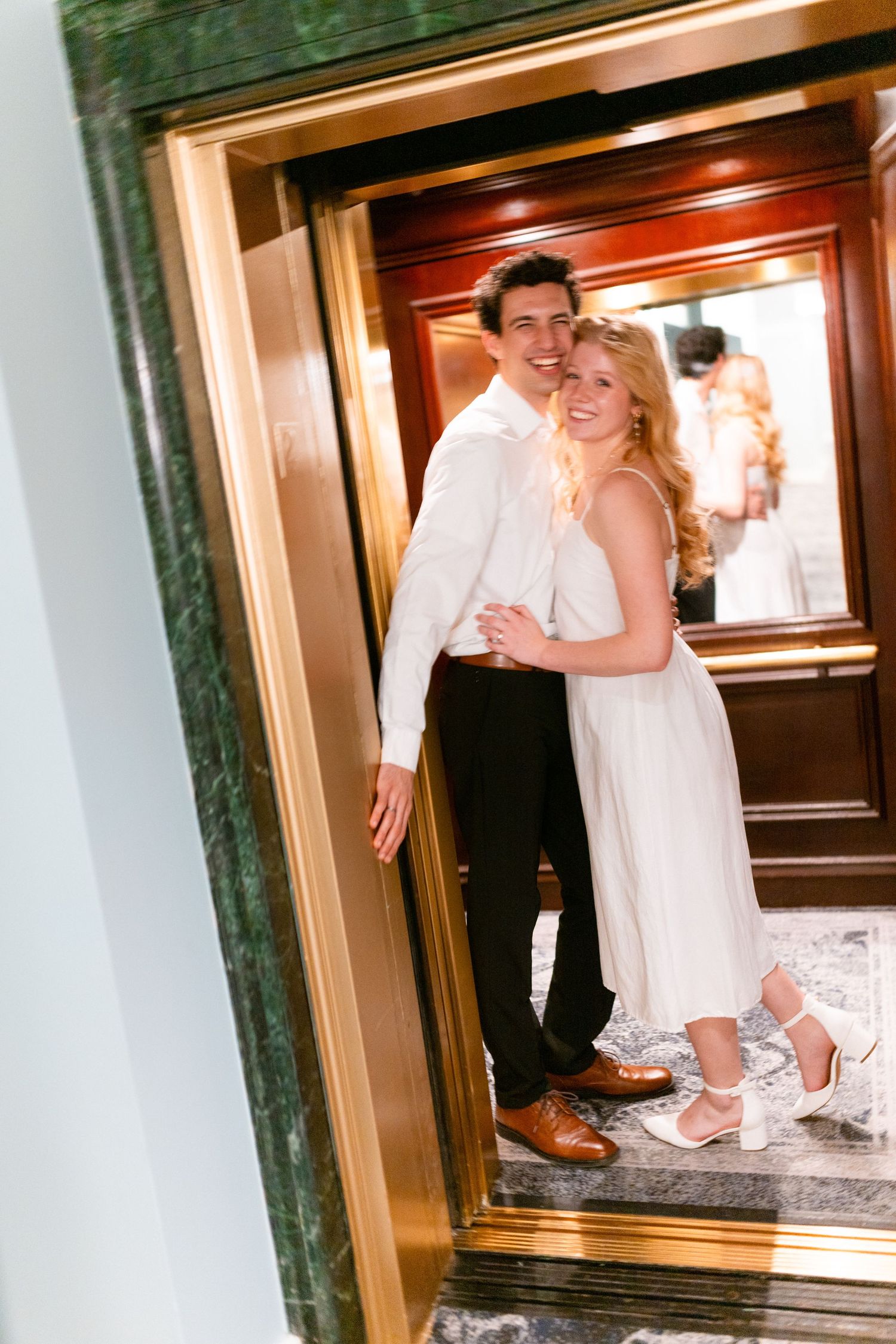 Close-up view of wedding shoes and formal attire at the bottom of an elevator door.
