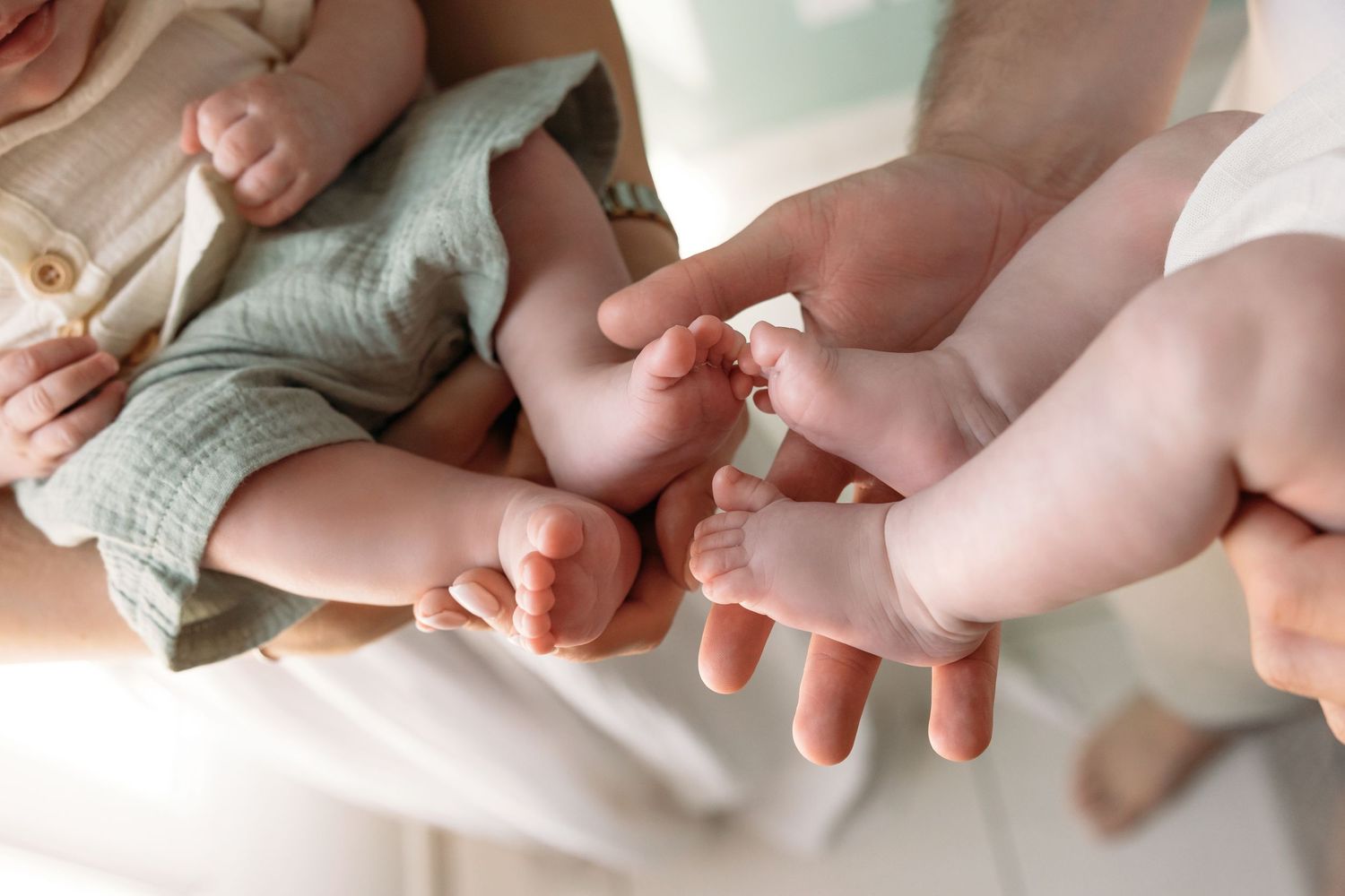 A close-up shot of a newborn baby’s tiny feet and hands being gently held by the parents, capturing the tender connection.