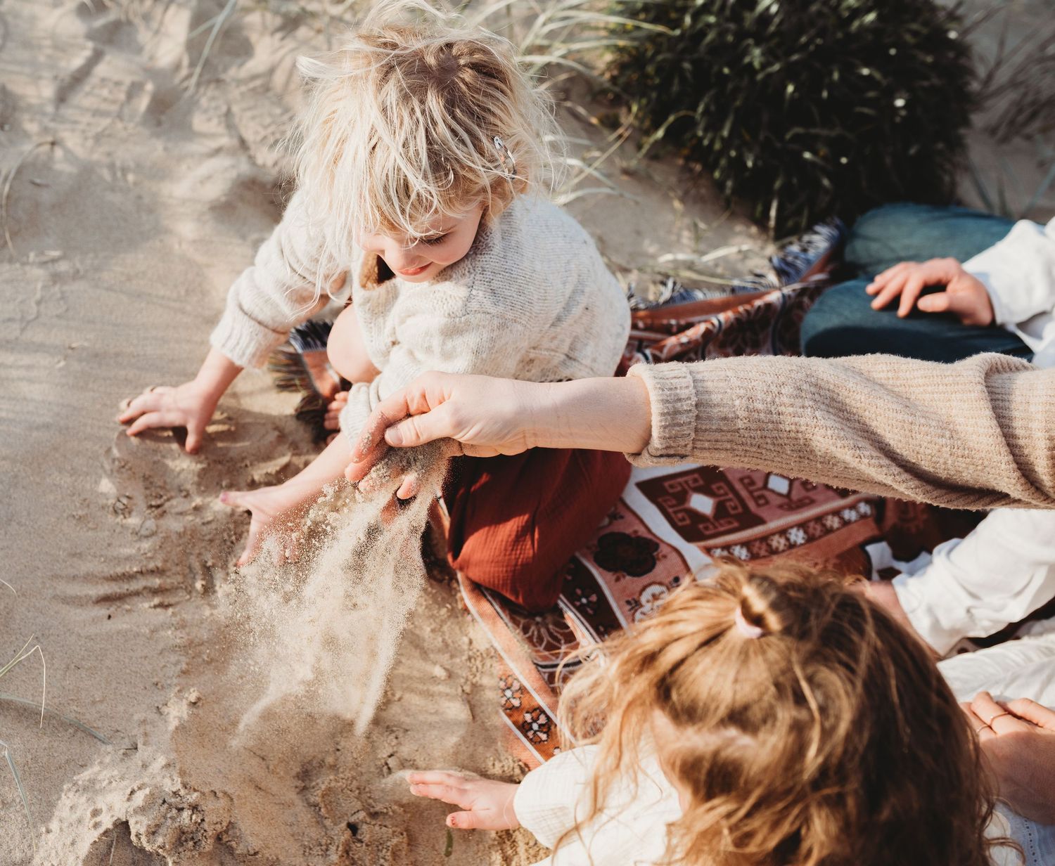 Family sitting together on rocky coastal ground during golden hour photography session.