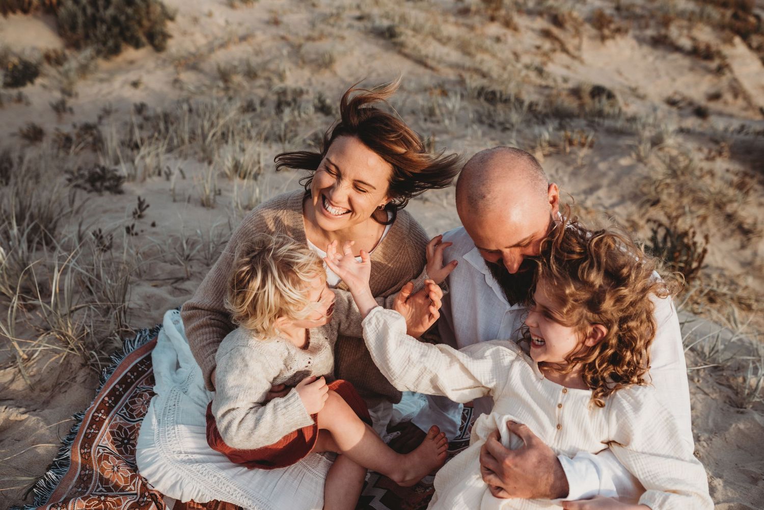 Family enjoying intimate moments together during beach photoshoot at sunset.