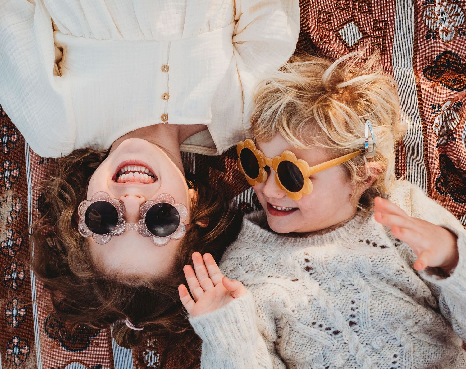 Candid moments captured on a patterned blanket during an outdoor photoshoot.